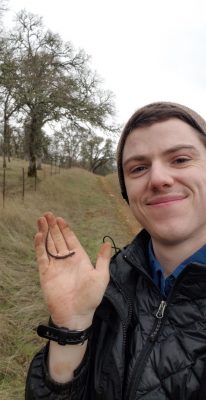 Nick smiling and holding a small brown salamander in his right hand